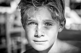 Black and white portrait of a smiling boy with freckles