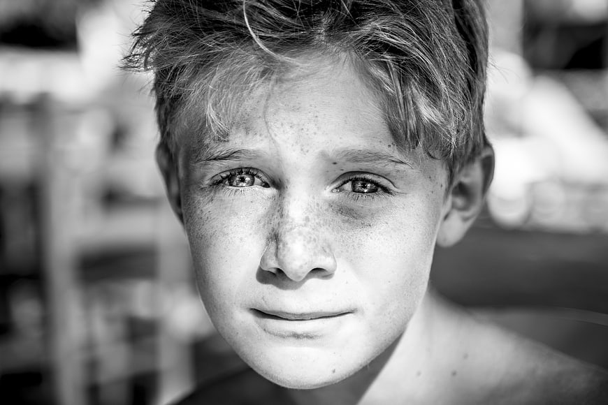 Black and white portrait of a smiling boy with freckles