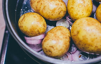 Close-up of raw potatoes and red onions in a cooking pot