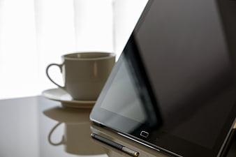 Tablet and Coffee Cup on Glossy Desk