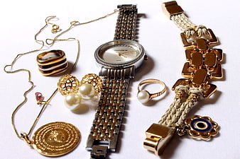 Flat lay of gold jewelry, watch, and accessories on white background