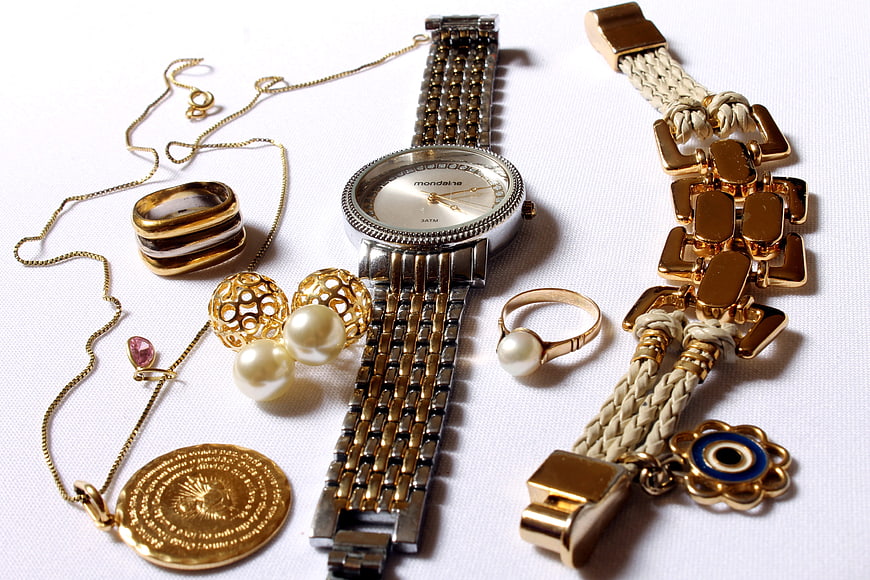 Flat lay of gold jewelry, watch, and accessories on white background