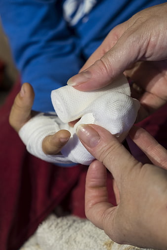 Close-up of adult bandaging child's injured finger