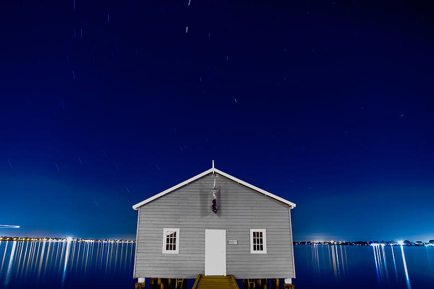 Boathouse with Star Trails and Water Reflections at Night