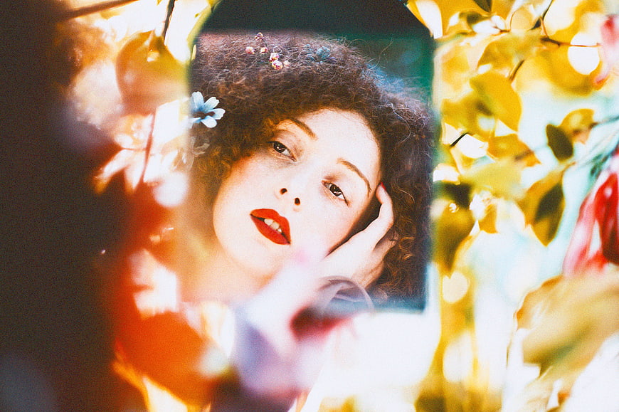 Woman with curly hair and red lipstick in mirror reflection