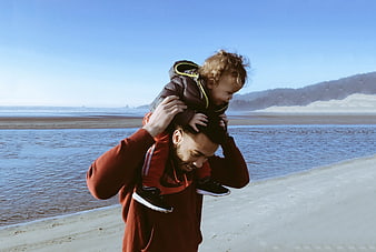 Happy Father Carrying Toddler on Shoulders at Beach