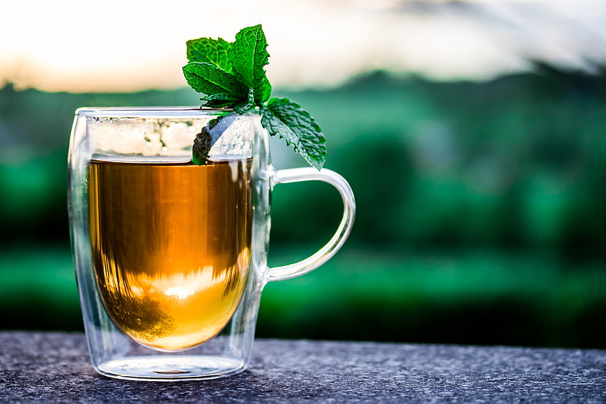 Fresh Mint Tea in Glass Cup with Green Nature Background