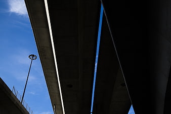 Low angle view of concrete highway overpass against blue sky