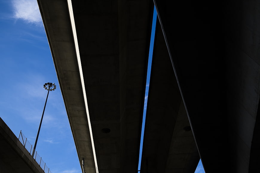 Low angle view of concrete highway overpass against blue sky