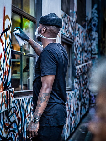 Man creating graffiti art on urban wall with spray paint