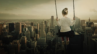 Little girl swinging high above a city skyline