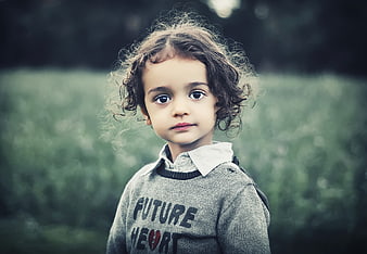 Portrait of a cute little girl with curly hair outdoors