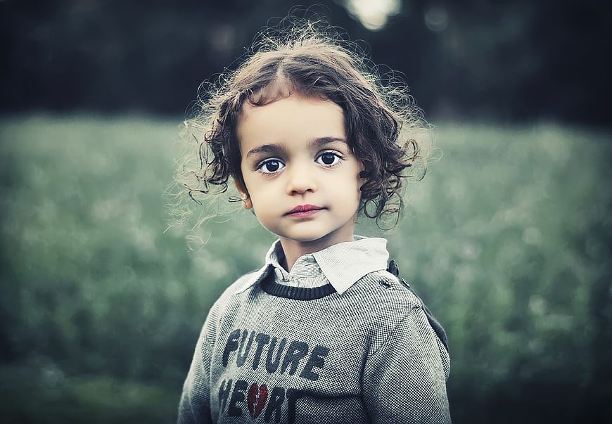 Portrait of a cute little girl with curly hair outdoors