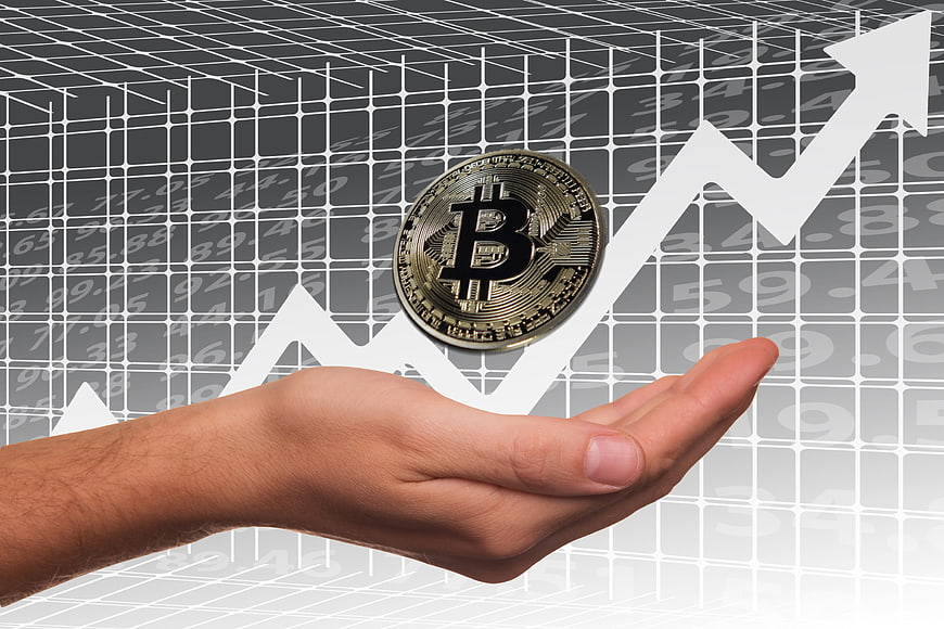 Hand holding Bitcoin coin over rising financial chart background
