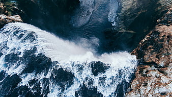 Aerial view of powerful ocean waves crashing against rocky cliffs