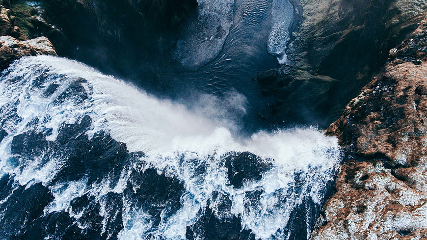 Aerial view of powerful ocean waves crashing against rocky cliffs
