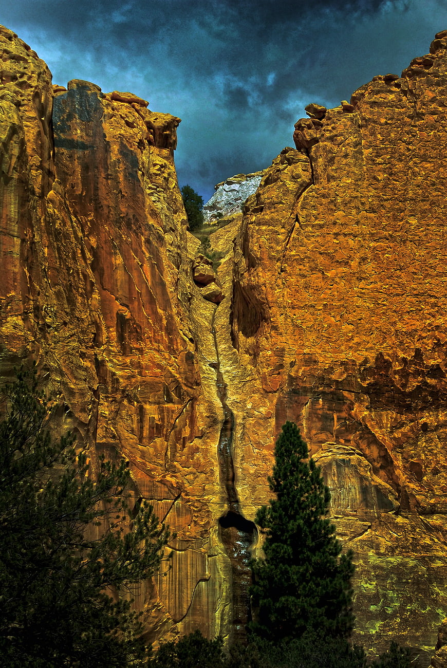 Dramatic Canyon Waterfall with Golden Rock Walls and Dark Sky