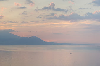 Serene Ocean Sunset with Distant Mountains and Pastel Sky