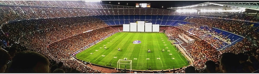 Wide panoramic view of a packed football stadium at night