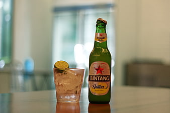 Bintang Radler beer bottle and iced drink with lime on table
