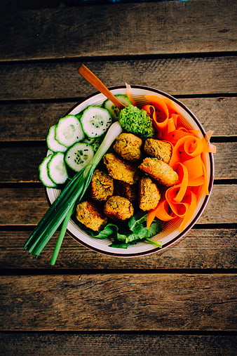 Top view of vegan falafel bowl with fresh vegetables on wood