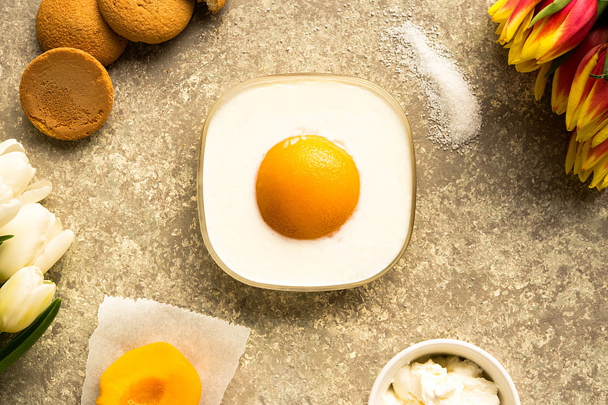 Creative egg-shaped cake with peach yolk and spring tulips