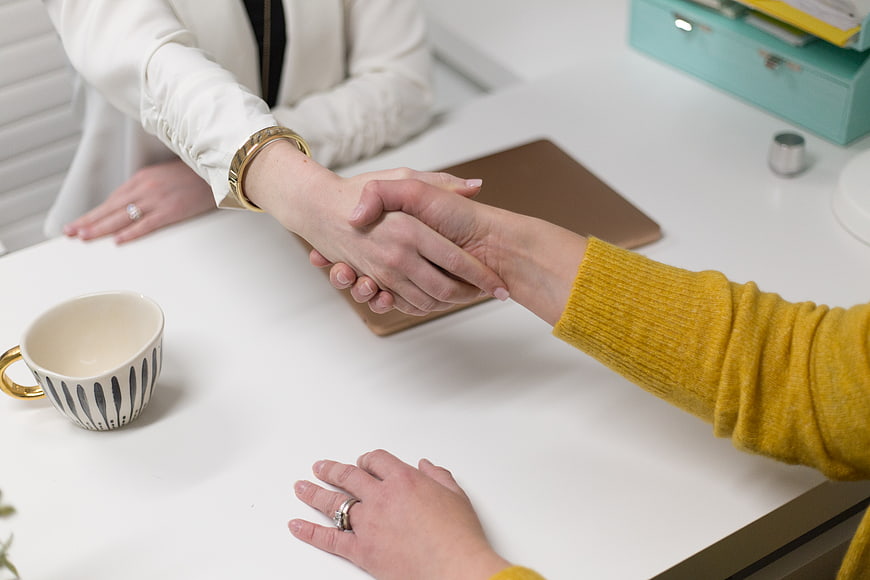 Business Handshake Between Two Women at Office Desk