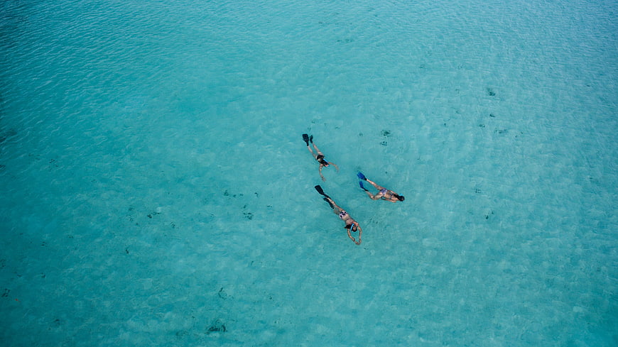 Aerial view of three snorkelers in turquoise ocean water