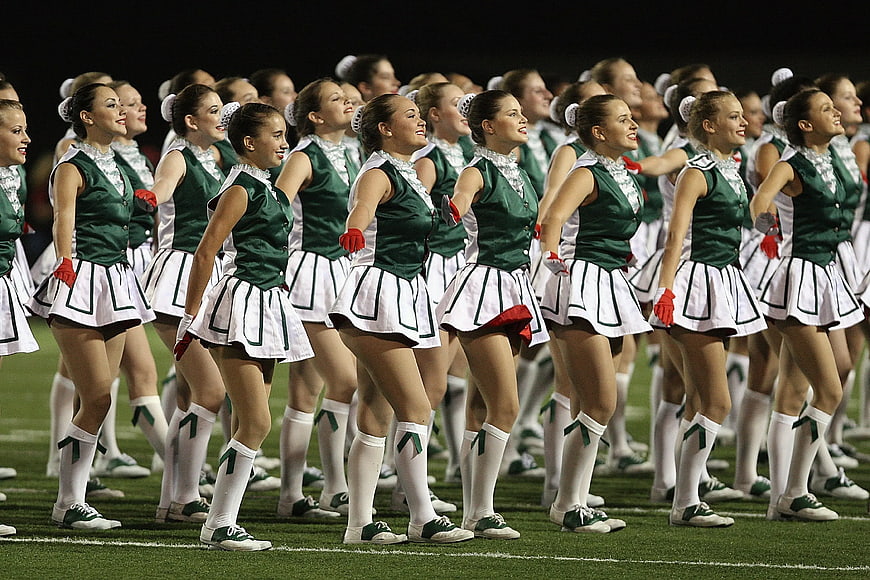 Cheerleaders in Green and White Uniforms on Football Field