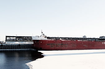 Large red cargo ship docked in icy winter harbor