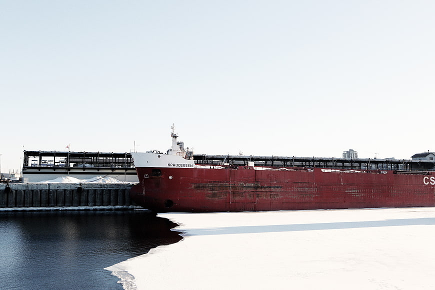 Large red cargo ship docked in icy winter harbor