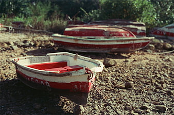 Weathered red and white boats resting on a rocky shore