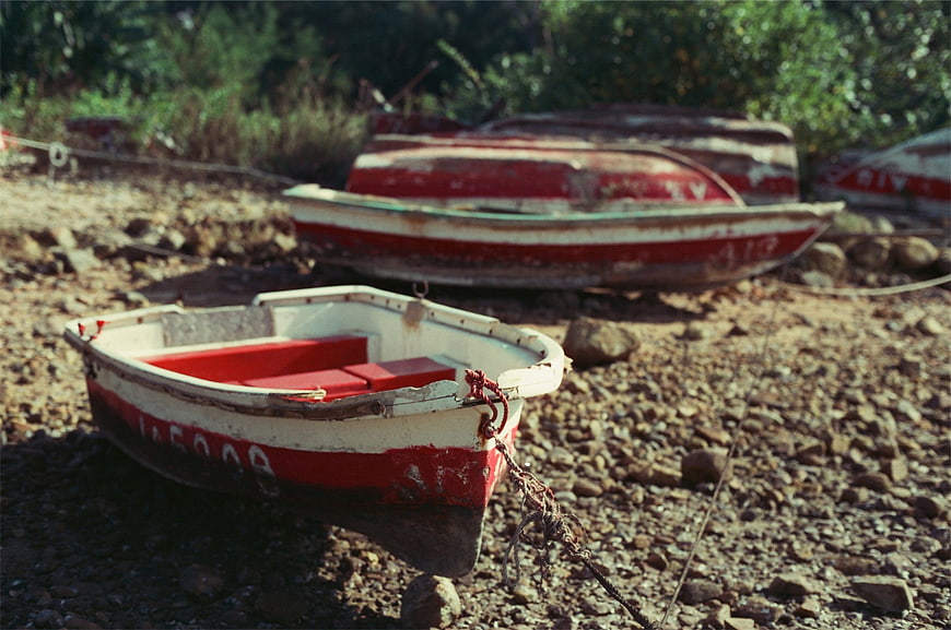 Weathered red and white boats resting on a rocky shore