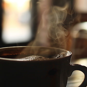 Close-up of steaming hot coffee in a dark mug