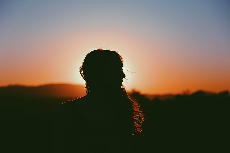 Silhouette of Woman Against Orange Sunset Sky