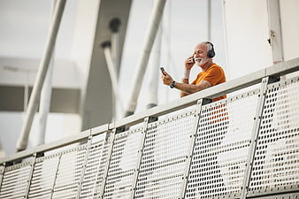 Senior man with headphones and smartphone on modern bridge