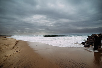 Moody Overcast Beach with Crashing Waves and Rocky Jetty