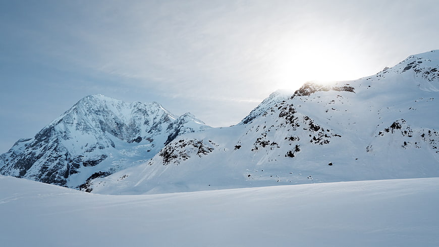 Snowy Mountain Peaks with Sunlight and Clear Sky