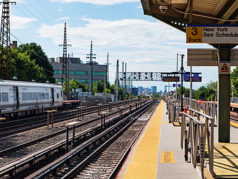Train Station Platform with Tracks and City Skyline