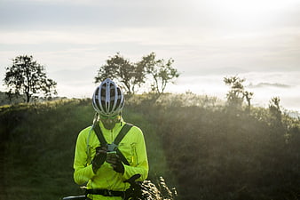Cyclist in Neon Jersey Checking Smartphone on Hilltop
