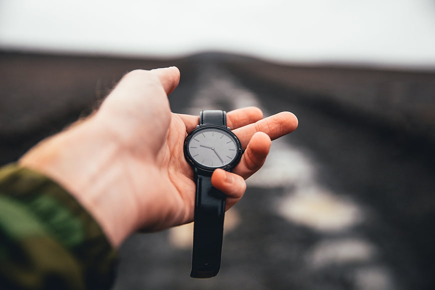 Hand Holding Minimalist Watch on Blurred Road