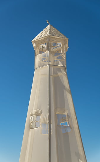 White fabric lighthouse sculpture against clear blue sky