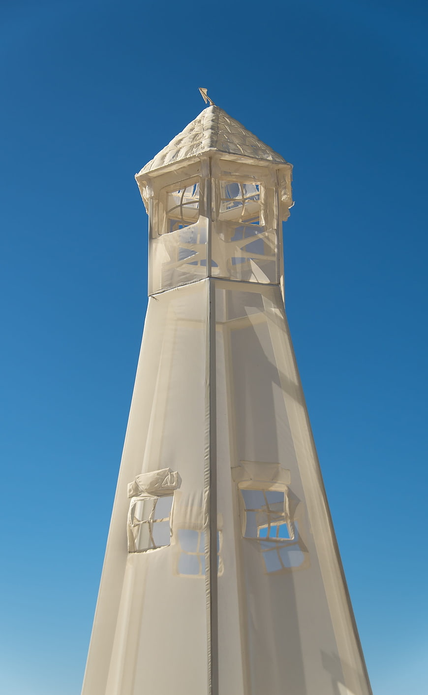 White fabric lighthouse sculpture against clear blue sky