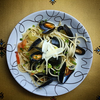 Overhead view of spaghetti with mussels and parmesan cheese