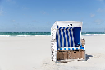 Blue and White Striped Beach Chair on Sandy Shore