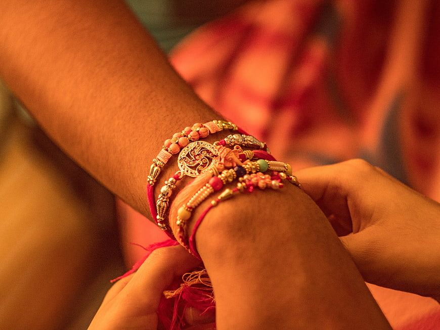 Close-up of hands tying traditional Rakhi bracelet during festival
