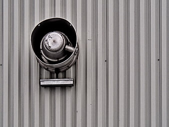 Weathered industrial metal vent on corrugated wall