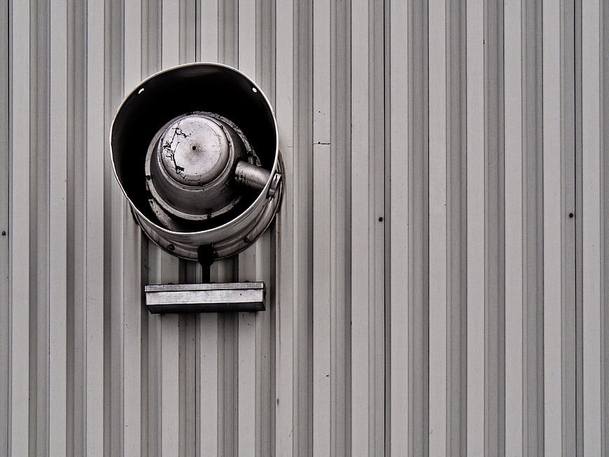 Weathered industrial metal vent on corrugated wall
