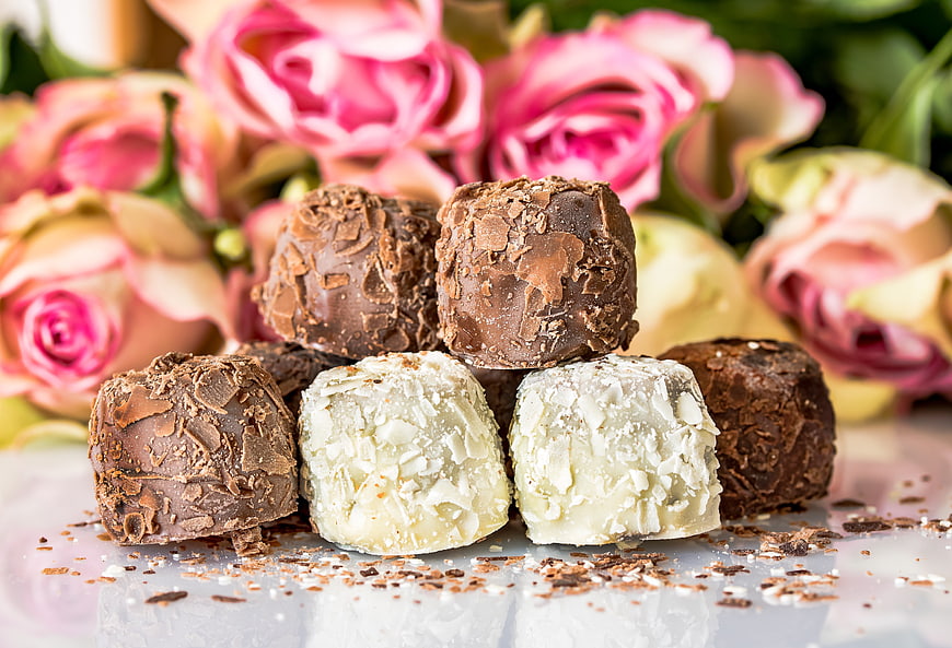 Gourmet Chocolate Pralines With Almond Toppings And Pink Roses