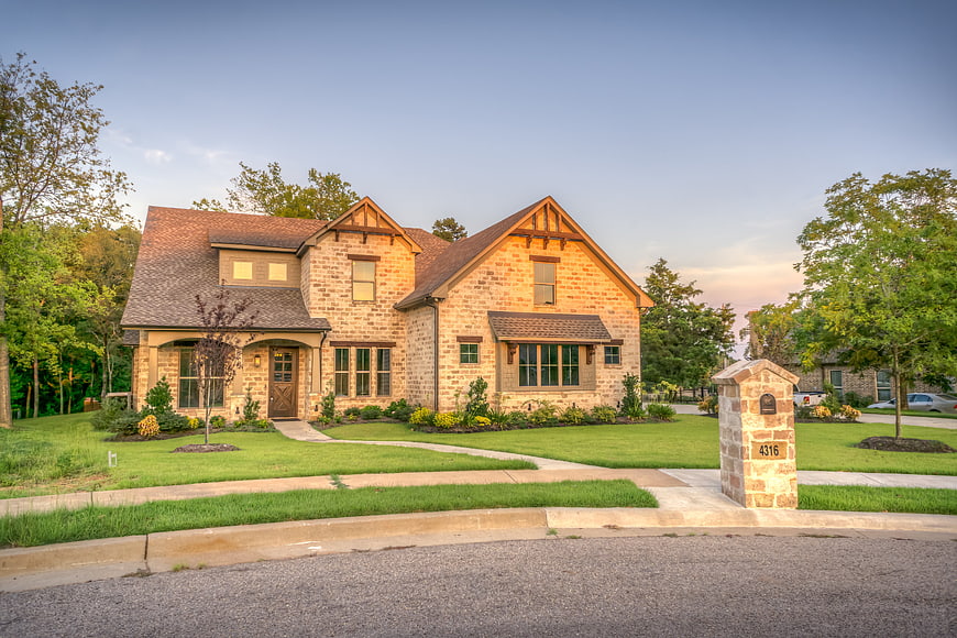 Luxury Brick Home Exterior With Landscaped Front Yard At Dusk